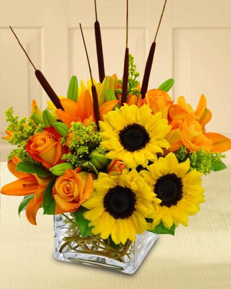 Autumn Breeze-Yellow sunflowers, orange tiger lilies, orange roses, cat tails, and solidago are crafted in a clear glass cube that is decoratively lined with curley willow.-Fall Arrangement

