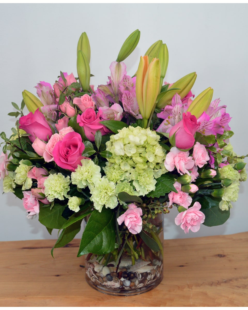 Beach Rose Garden Deluxe-in cylinder This beautiful arrangement features green hydrangea, hot pink roses, pink spray roses, peach asiatic lilies, pink alstroemeria, green carnations, pink miniature carnations, seeded eucalyptus, parvifolia eucalyptus, and lemon leaf.Designed in a rustic wood cube.
DELIVERY: Every order is hand-delivered direct to the recipient. These items will be delivered by us locally, or a qualified, retail, local florist.
